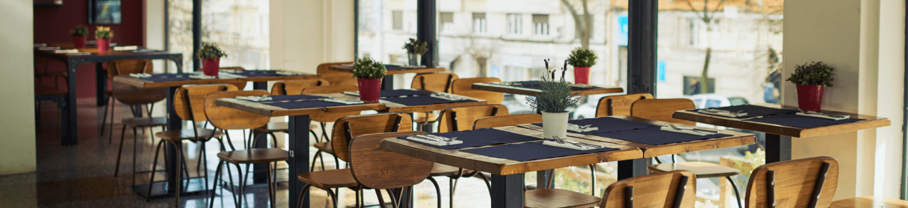 Image contains an empty restaurant with pre-set tables as an example of a business who would need commercial general liability insurance