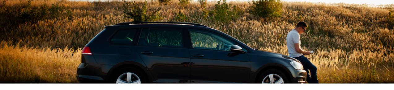 Man leaning against the hood of his SUV on the roadside shows an example of someone who needs auto insurance in sc