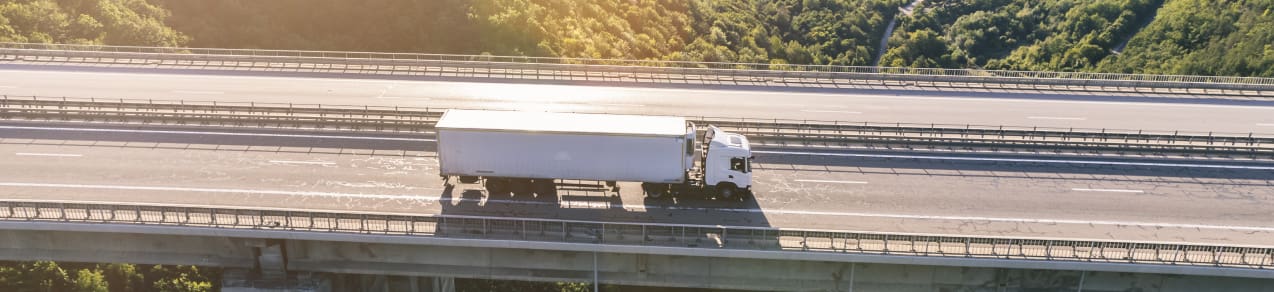 Long Haul truck driving along a highway bridge showing an image of a business that would need commercial auto insurance.