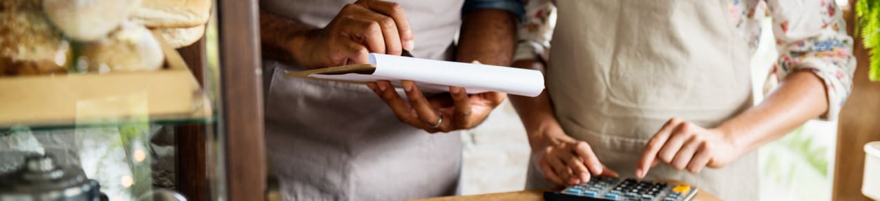 Image of a business owner showing an employee how to compute some figures in their shop as an example of a business that could use employment practices liability insurance