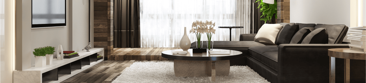 Elegant home living room with large sectional sofa, round solid wood coffee table, and flatscreen tv showing an example of a home that should have homeowners insurance.